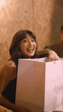 a woman is smiling while holding a dyson bag
