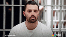 a man in a white shirt sits in a jail cell with #chicagopd on the bottom