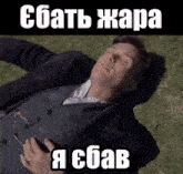 a man in a suit is laying in the grass with a foreign language caption