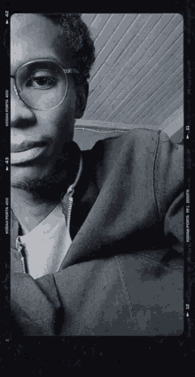 a black and white photo of a man wearing glasses and a kodak film strip