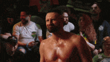 a man without a shirt is standing in front of a crowd with a w logo in the background