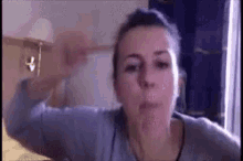 a woman is making a funny face while sitting on a bed in a room .