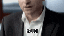 a man in a suit and white shirt is saying hallo in german .