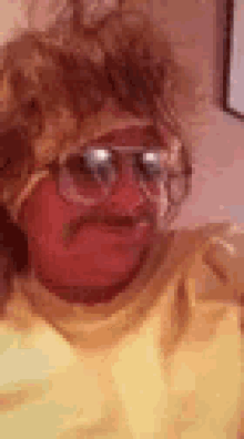 a man with glasses and a mustache is wearing a yellow shirt and a wig .