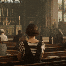 a woman in a striped shirt is sitting in a church with a caption that says @itsscottiesstark