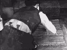 a black and white photo of a man cleaning a rug
