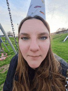 a woman wearing a paper hat with cars on it looks at the camera