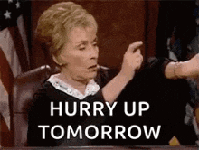a woman is sitting at a table with a sign that says hurry up tomorrow on it .
