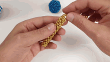 a person is holding a bracelet made of gold beads