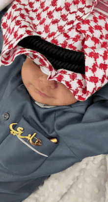 a baby wearing a keffiyeh and a blue shirt with arabic writing on the pocket