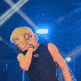 a man singing into a microphone while wearing a black shirt with the letter s on it