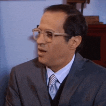 a man wearing glasses and a suit is making a surprised face