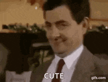 a man in a suit and tie is making a funny face and says `` cute '' .