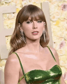 taylor swift is wearing a green sequined dress and earrings at awards .