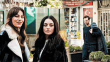 a man and two women are standing in front of a store with a flag on it