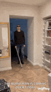 a blind man is walking through a hallway holding a cane with the caption " the blind man is coming over today "