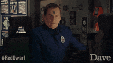 a man with a h on his forehead is sitting in front of a computer monitor