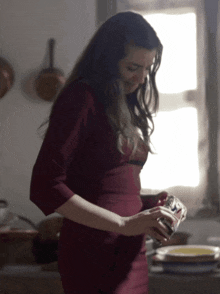 a woman in a red dress holds a jar of something
