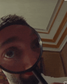 a man is looking through a magnifying glass at his face