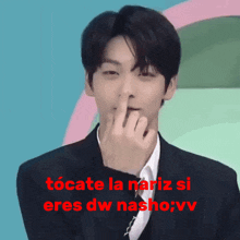 a man in a suit and tie holds his finger to his nose and says " tocate la nariz si "