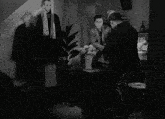 a black and white photo of a room with a telephone and flowers