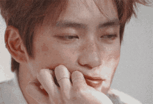 a close up of a man 's face with his hand on his chin