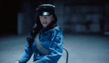 a woman in a blue uniform is sitting in a chair with a gun .