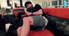 a man is sitting on a couch with his legs crossed and a mask on his face .