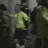 a man in a yellow shirt is standing in a crowd of people in a room .
