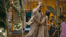 a man in a suit is holding a woman in a sari while dancing in a room .