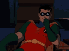 robin from the batman animated series is sitting in a chair and wearing a red and green costume .