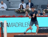 a man is playing tennis in front of a sign that says amadrilen