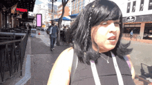 a woman is walking down a sidewalk in front of a building that says ' therapy ' on it