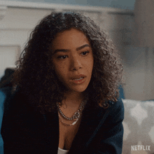 a woman with curly hair is sitting on a couch with a netflix logo on the bottom