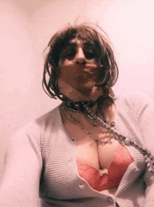 a woman wearing a choker and a bra is smoking a cigarette and taking a selfie .