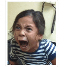 a little girl in a striped shirt is screaming with her mouth open .