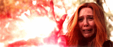 a woman with red hair is crying in front of a tree .