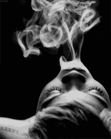 a black and white photo of a woman smoking with smoke coming out of her mouth