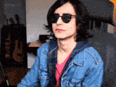 a man wearing sunglasses and a denim jacket is sitting in a chair