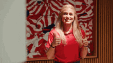 a woman in a red shirt is giving a thumbs up sign