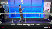 a man stands in front of a sign that says iheartfestival2019