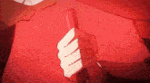 a close up of a person 's hand holding a red object in a red background .