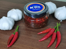 a jar of king lee chili garlic is surrounded by garlic and red peppers