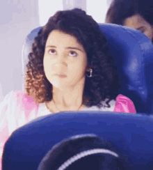 a girl with curly hair is sitting in a blue chair