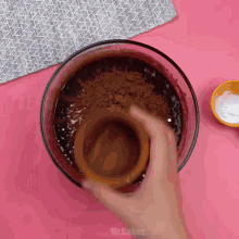 a person is pouring cocoa powder into a bowl of chocolate sauce