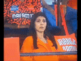 a woman in an orange shirt is sitting in a stadium with an orange pillow that says dream army .