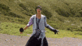 a man in a white shirt and black gloves is standing on a dirt road