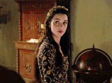 a woman with a crown on her head is standing in front of a globe