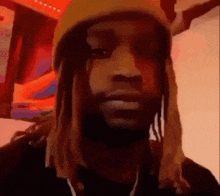 a man with dreadlocks wearing a yellow beanie and headphones .