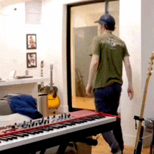 a man in a green shirt walks past a keyboard